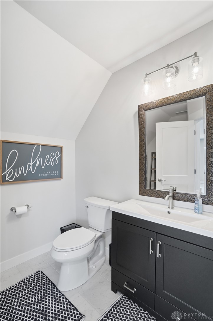 9364 Kenrick Road Dayton, OH 45458 - Photo 40 of 62 This bright bathroom features a vanity, toilet, and elegant mirror, creating a functional space.
