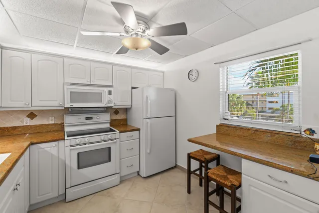 a kitchen with granite countertop white cabinets and white appliances