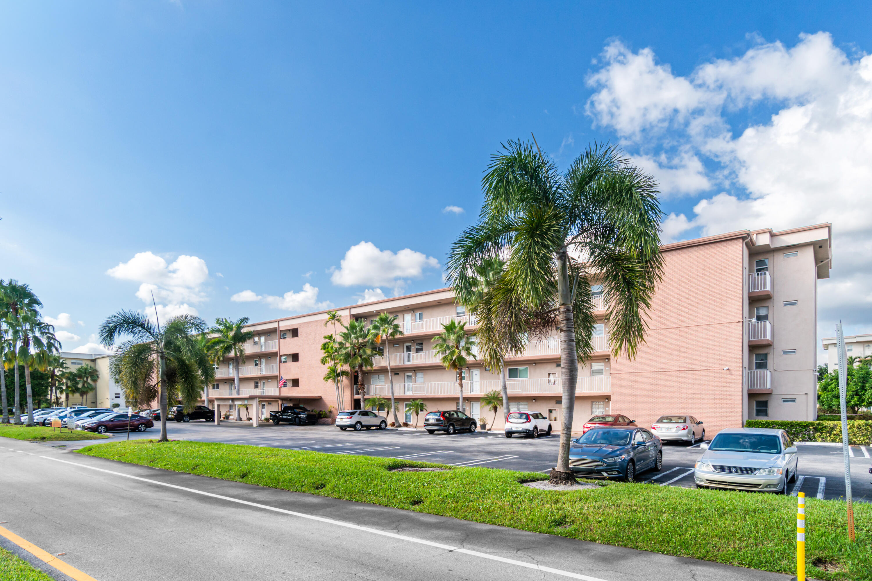 2615 Northeast 1st Court, Unit 303 Boynton Beach, FL 33435 - Photo 2 of 42 a front view of a building with garden and trees