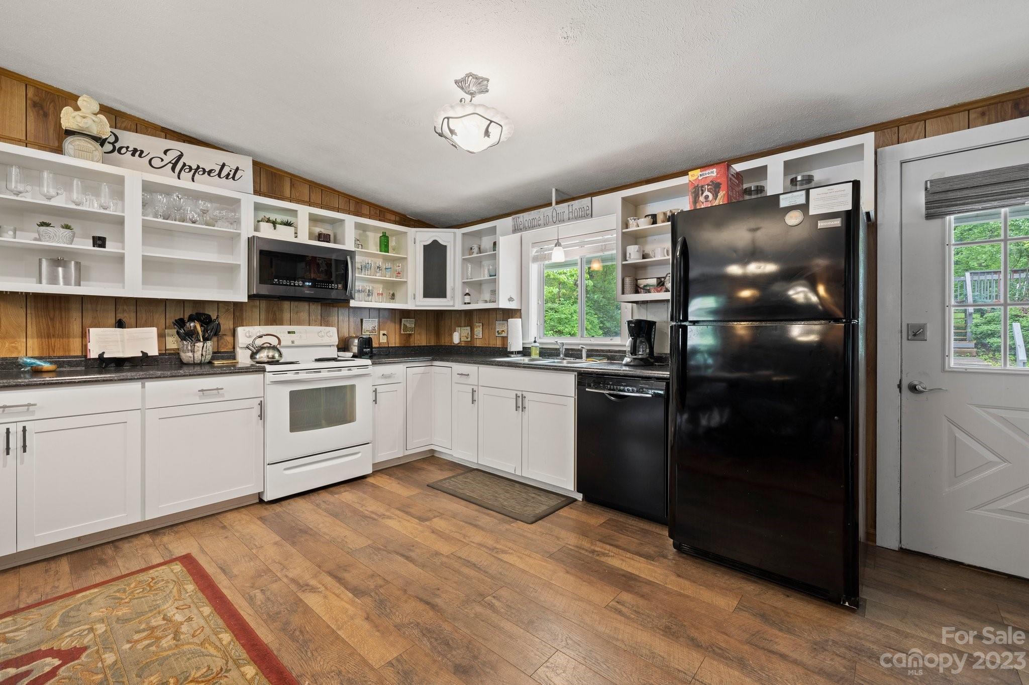 1545 Brevard Road Asheville, NC 28806 - Photo 11 of 43 a kitchen with stainless steel appliances granite countertop a refrigerator a sink dishwasher a stove with white cabinets and wooden floor