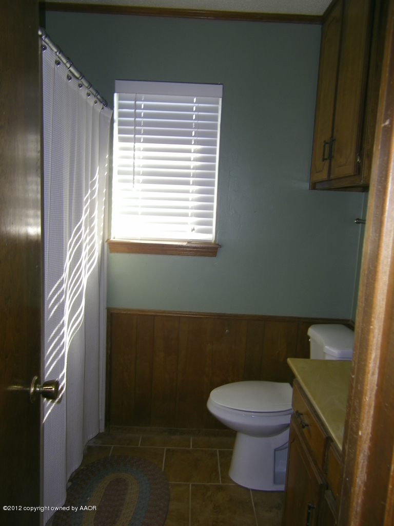 5714 South Milam Street Amarillo, TX 79110 - Photo 12 of 22 a bathroom with a toilet a sink and a window
