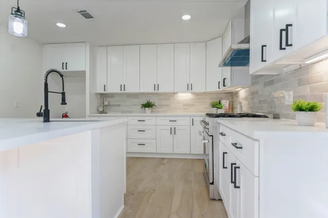 a kitchen with granite countertop a sink white cabinets and stainless steel appliances