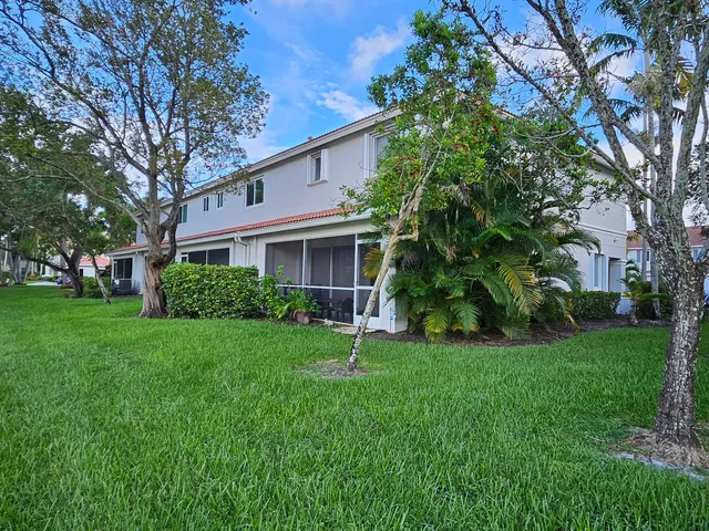 a house in front of a house with plants and large trees