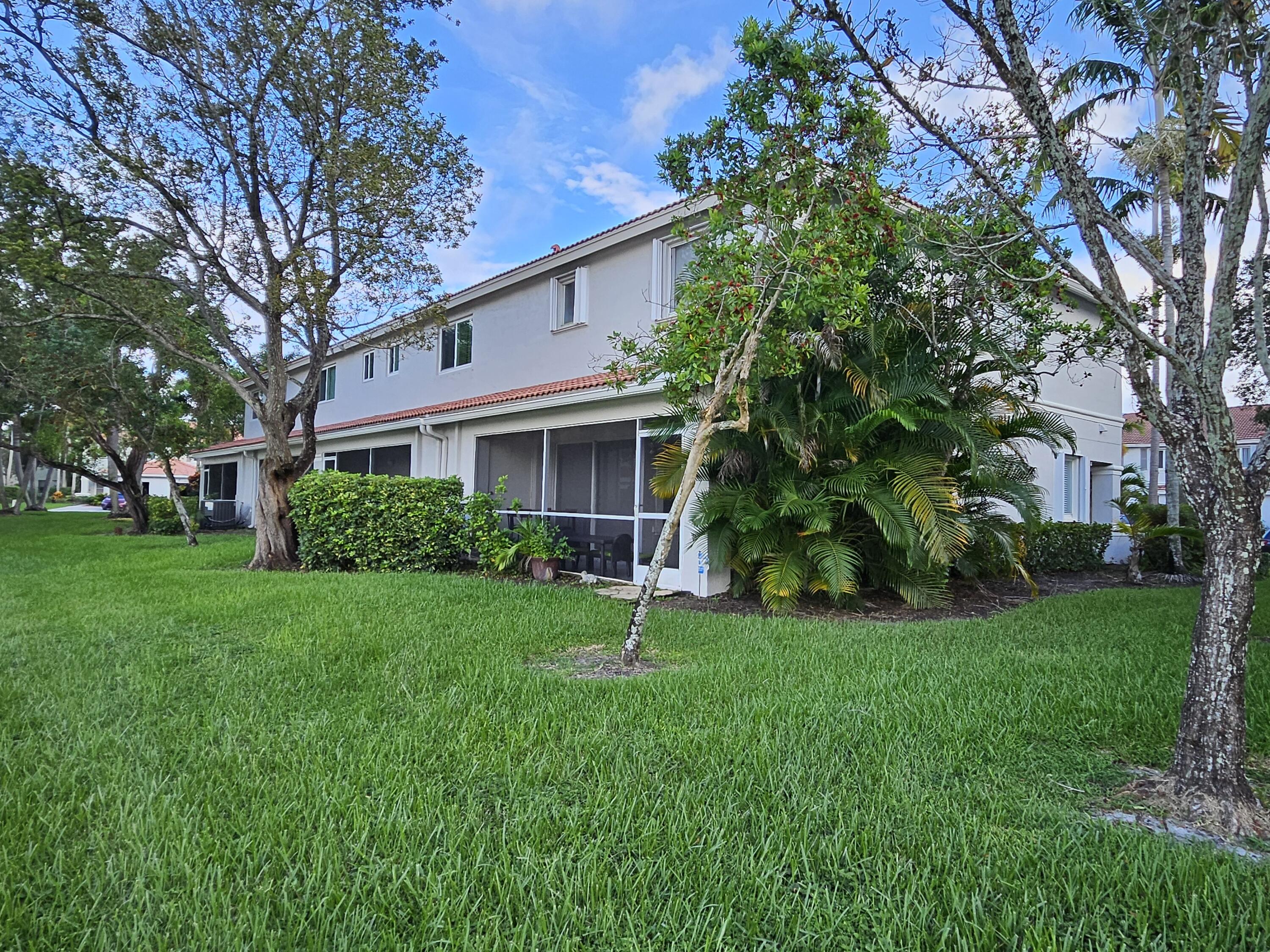 8027 Big Pine Way Riviera Beach, FL 33407 - Photo 2 of 6 a house in front of a house with plants and large trees