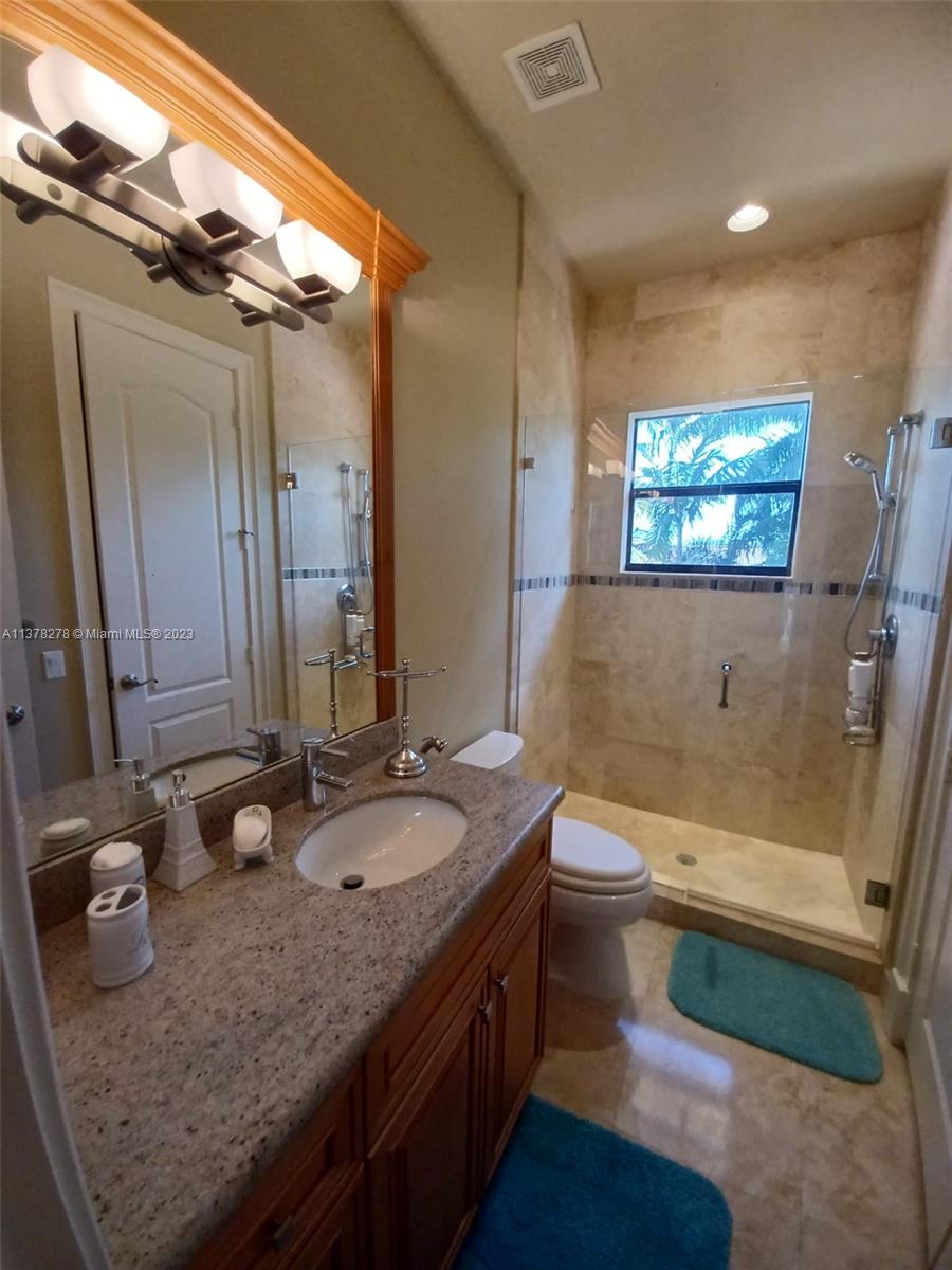 19349 Waters Edge Street Weston, FL 33332 - Photo 36 of 63 a bathroom with a granite countertop sink a toilet a mirror and bathtub
