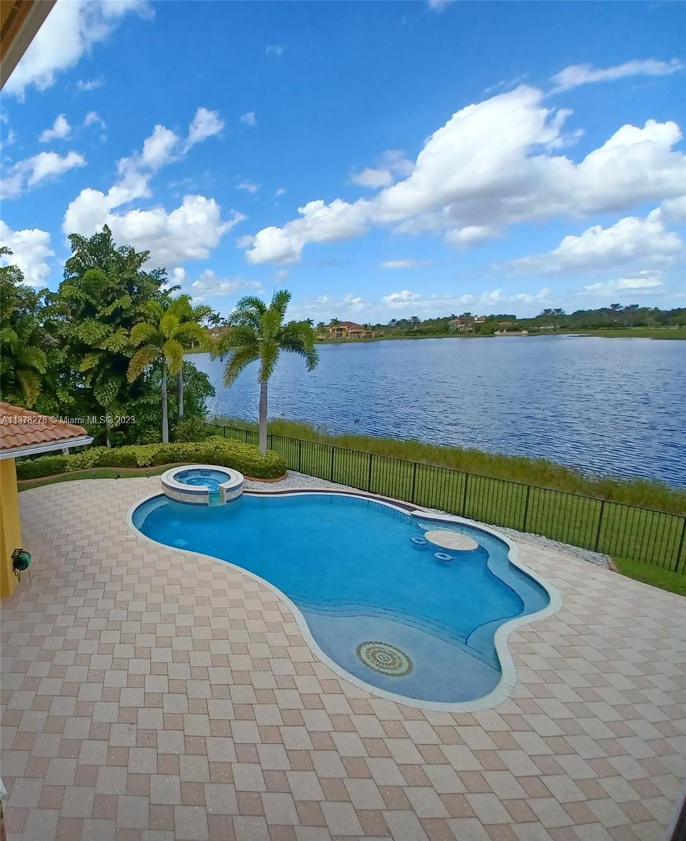 19349 Waters Edge Street Weston, FL 33332 - Photo 44 of 63 a view of a swimming pool with lake and houses in the back