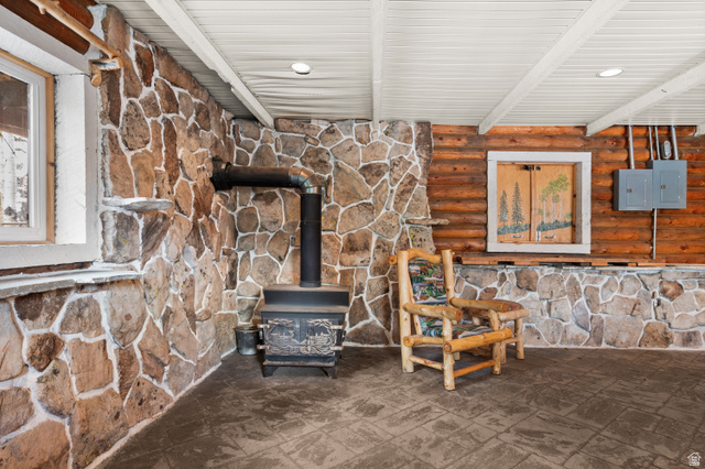 4725 Pine Ridge Road Evanston, UT 82930 - Photo 24 of 82 Stone-accented walls featuring a wood-burning stove with metal flue