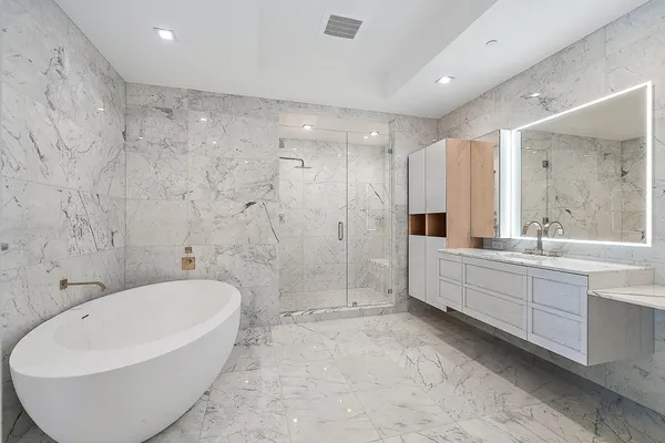 a large spacious bathroom with a tub shower sink and mirror