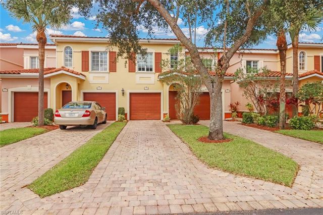 a front view of a house with a garden and trees