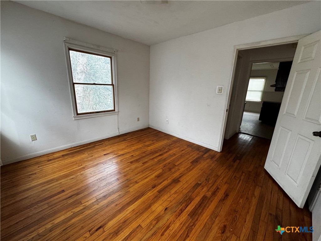 1010 South 17th Street Temple, TX 76504 - Photo 21 of 30 an empty room with wooden floor and windows
