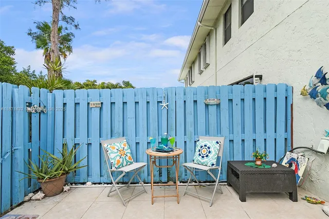 a backyard of a house with table and chairs with plants