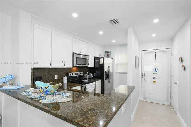 a kitchen with stainless steel appliances granite countertop a sink refrigerator and cabinets