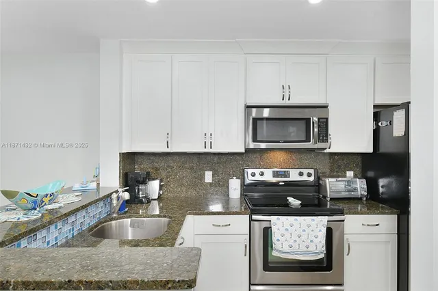a kitchen with granite countertop a sink a stove and cabinets