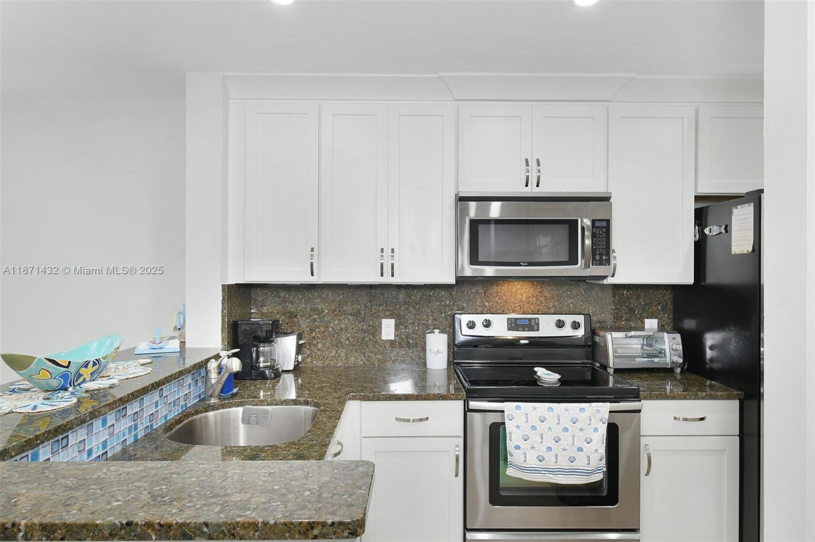 9421 South Ocean Drive, Unit 90 Jensen Beach, FL 34957 - Photo 7 of 49 a kitchen with granite countertop a sink a stove and cabinets