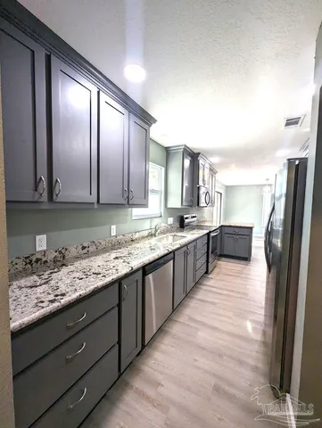 a large kitchen with granite countertop a large counter top stainless steel appliances and cabinets