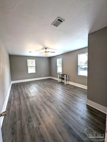 a view of empty room with wooden floor and fan