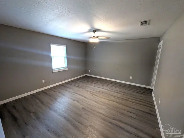 an empty room with wooden floor chandelier fan and windows