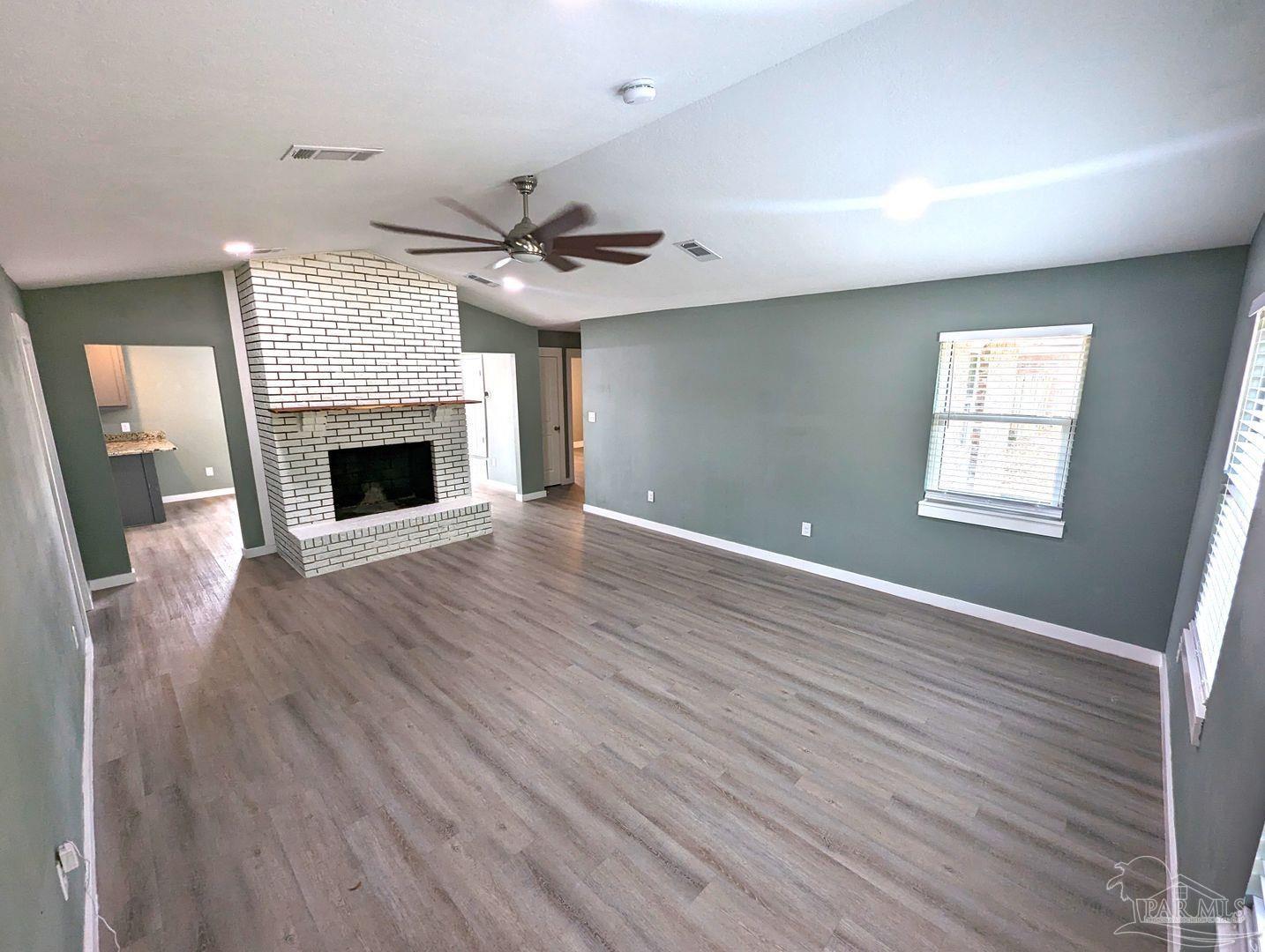 6045 Hamilton Bridge Road Milton, FL 32570 - Photo 2 of 31 a view of an empty room with wooden floor fireplace and a window