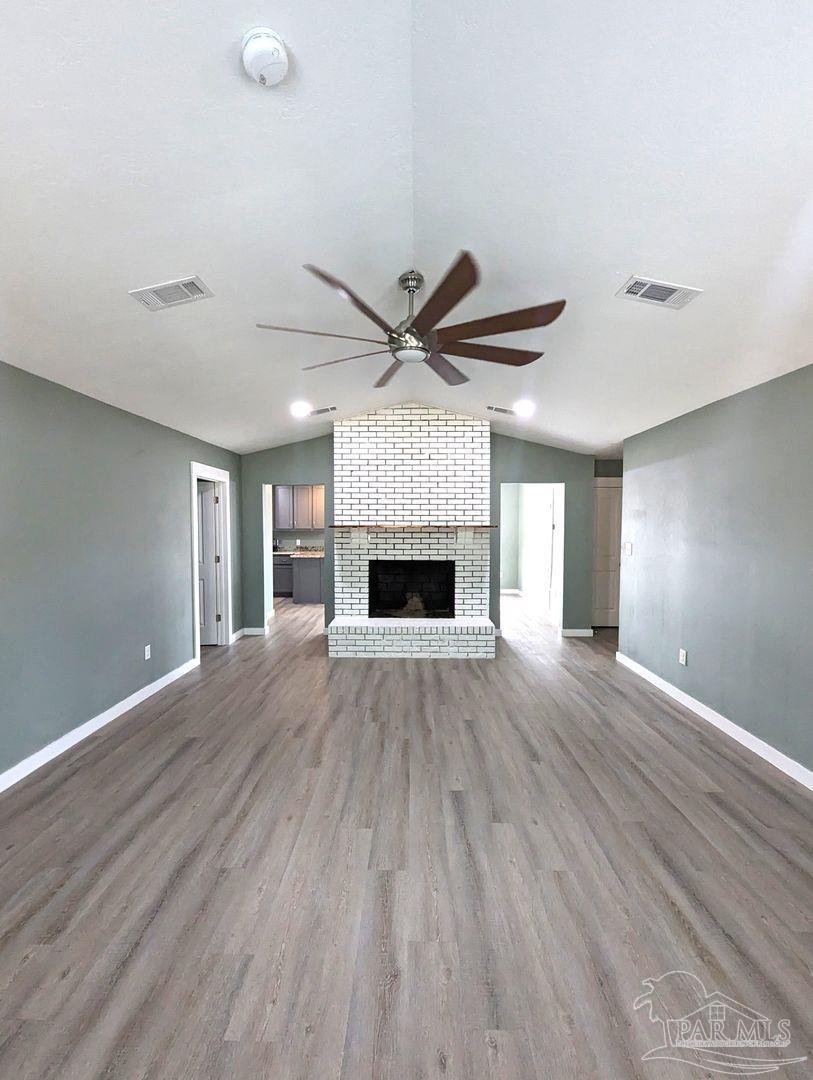 6045 Hamilton Bridge Road Milton, FL 32570 - Photo 4 of 31 an empty room with wooden floor a ceiling fan a fireplace and a ceiling fan