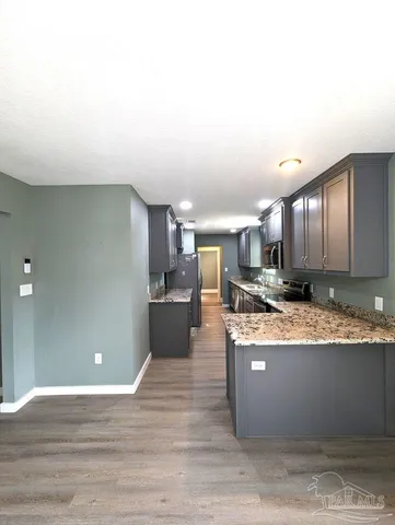 a large room with kitchen island a sink a stove and wooden floor