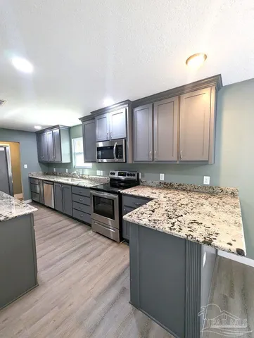 a large kitchen with kitchen island granite countertop wooden cabinets a granite counter tops and a sink