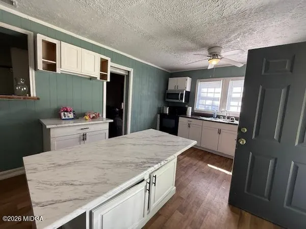 a kitchen with stainless steel appliances kitchen island granite countertop a refrigerator a sink dishwasher and a stove with wooden floor