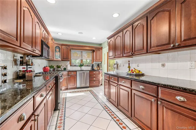 a kitchen with stainless steel appliances granite countertop a stove sink cabinets and window