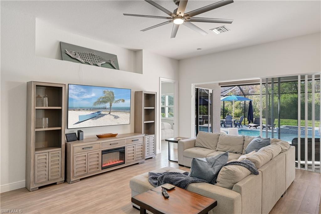 9121 Quartz Lane Naples, FL 34120 - Photo 11 of 36 Living area with ceiling fan, a sunroom, light wood finished floors, and a glass covered fireplace
