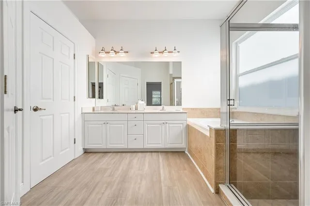 a spacious bathroom with a double vanity sink a mirror and a shower