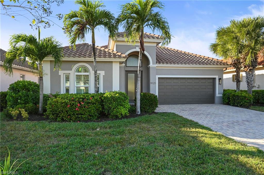 9121 Quartz Lane Naples, FL 34120 - Photo 2 of 36 Mediterranean / spanish-style home featuring stucco siding, decorative driveway, a garage, a tiled roof, and a front lawn