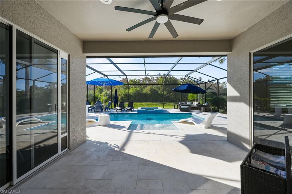 9121 Quartz Lane Naples, FL 34120 - Photo 29 of 36 View of pool with a patio, a sunroom, a pool with connected hot tub, glass enclosure, and an outdoor hangout area