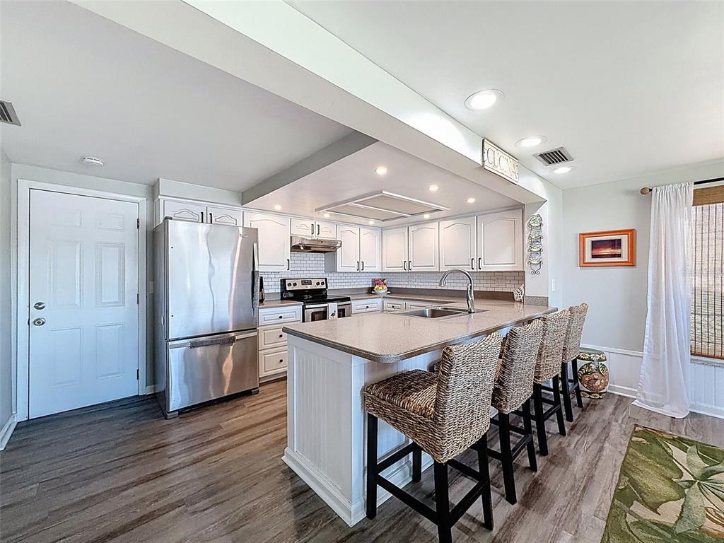 6521 Leeside Isle Hudson, FL 34667 - Photo 11 of 59 a kitchen with stainless steel appliances granite countertop a refrigerator a stove a sink a dining table and chairs with wooden floor