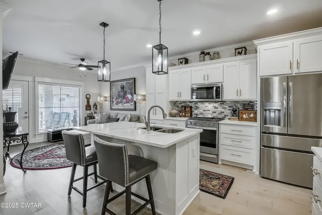 a kitchen with stainless steel appliances granite countertop a stove a sink a refrigerator a microwave oven with a dining table and chairs