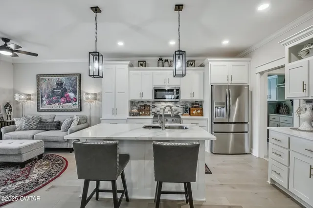 a kitchen with stainless steel appliances granite countertop a refrigerator a sink dishwasher a oven a dining table and chairs with wooden floor