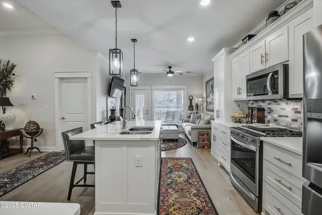a kitchen with kitchen island granite countertop a sink appliances cabinets and furniture
