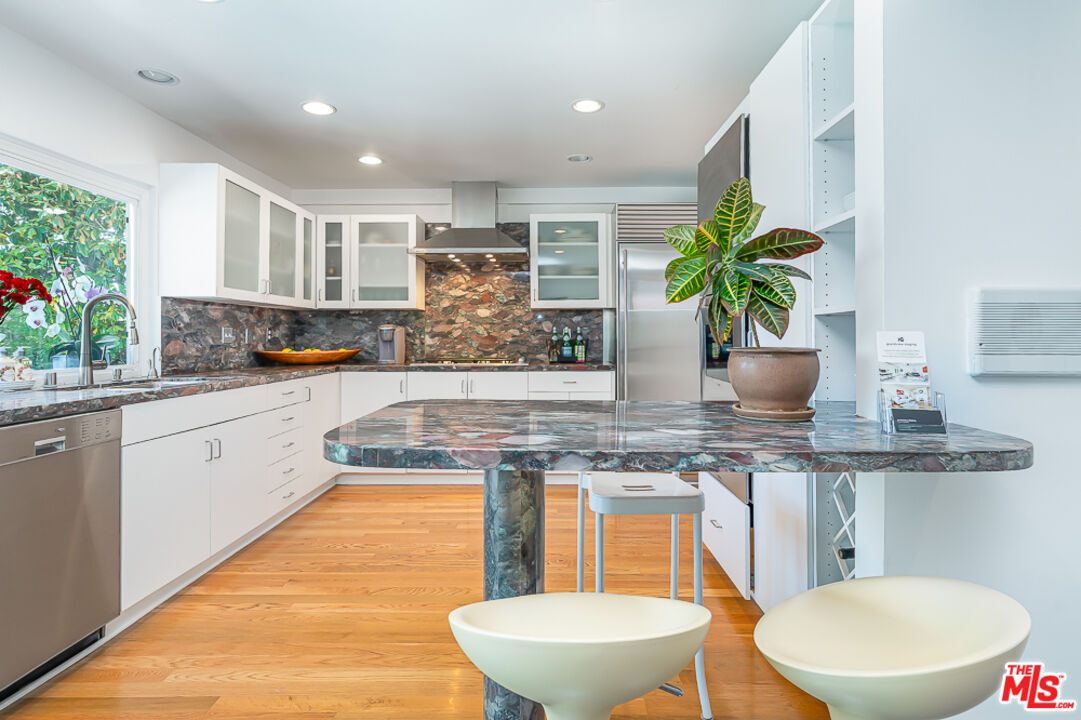 2866 Angelo Drive Los Angeles, CA 90077 - Photo 10 of 31 a kitchen with a stove a sink and a white wooden cabinets
