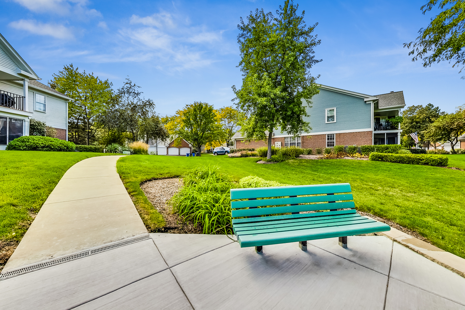 816 Butternut Lane, Unit C Mount Prospect, IL 60056 - Photo 31 of 32 a wooden bench sitting in middle of grass and trees in the background