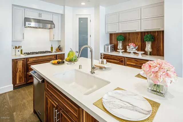 a kitchen with a sink a stove and chairs with wooden floor