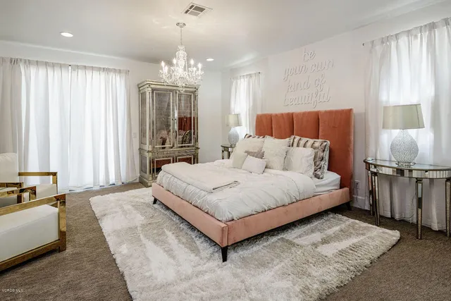 a spacious bedroom with a large bed and a chandelier