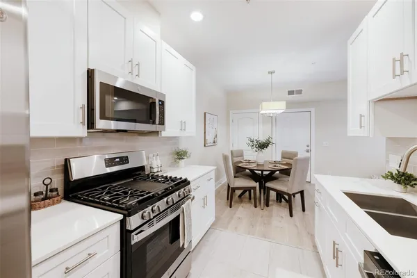 a kitchen with stainless steel appliances a stove a sink a microwave and chairs