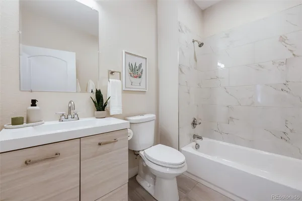 a bathroom with a granite countertop sink a toilet and a bathtub