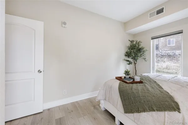 a bedroom with a bed and a potted plant next to a window