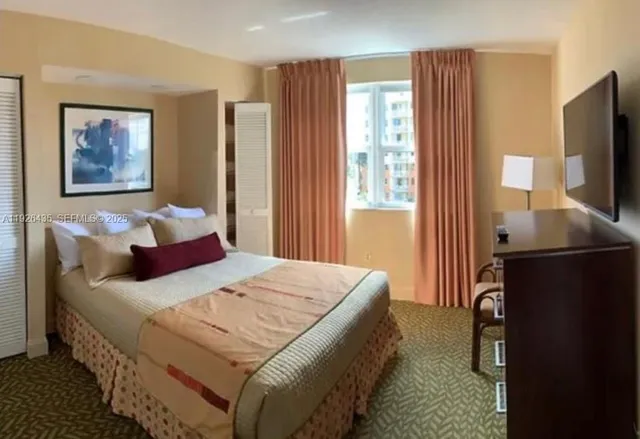 a bedroom with a bed flat screen tv and window