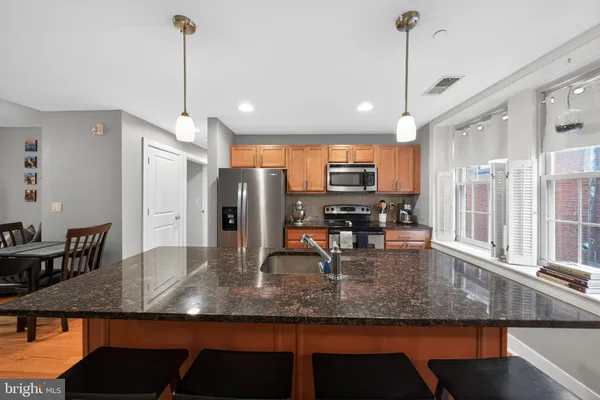 a view of a kitchen with kitchen island a counter top space a sink appliances and cabinets
