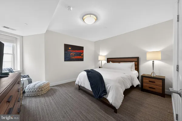 a bedroom with a bed and a flat tv screen on dresser