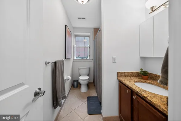 a bathroom with a granite countertop sink a toilet and a mirror
