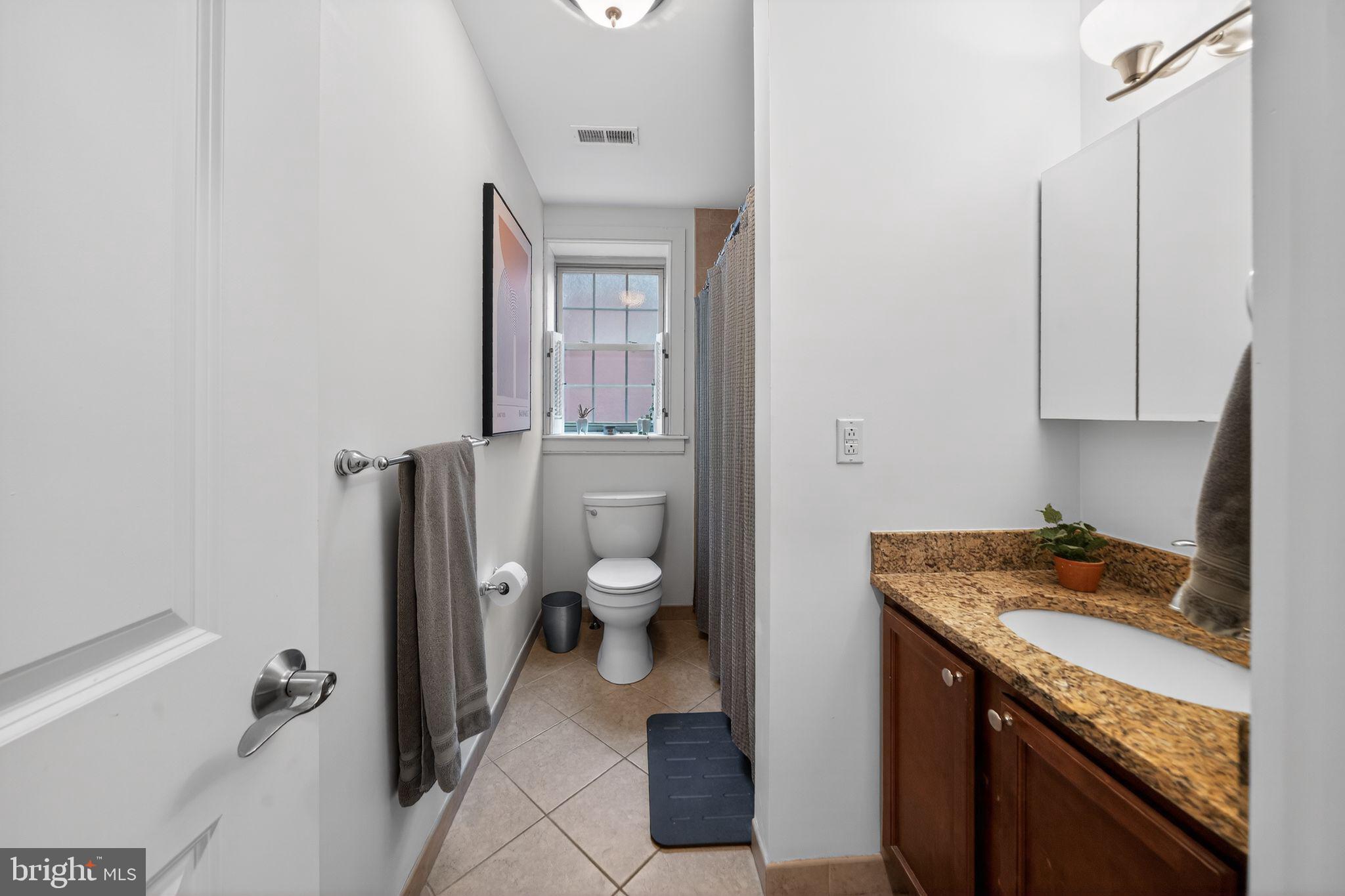 4300 Spruce Street, Unit B304 Philadelphia, PA 19104 - Photo 23 of 26 a bathroom with a granite countertop sink a toilet and a mirror