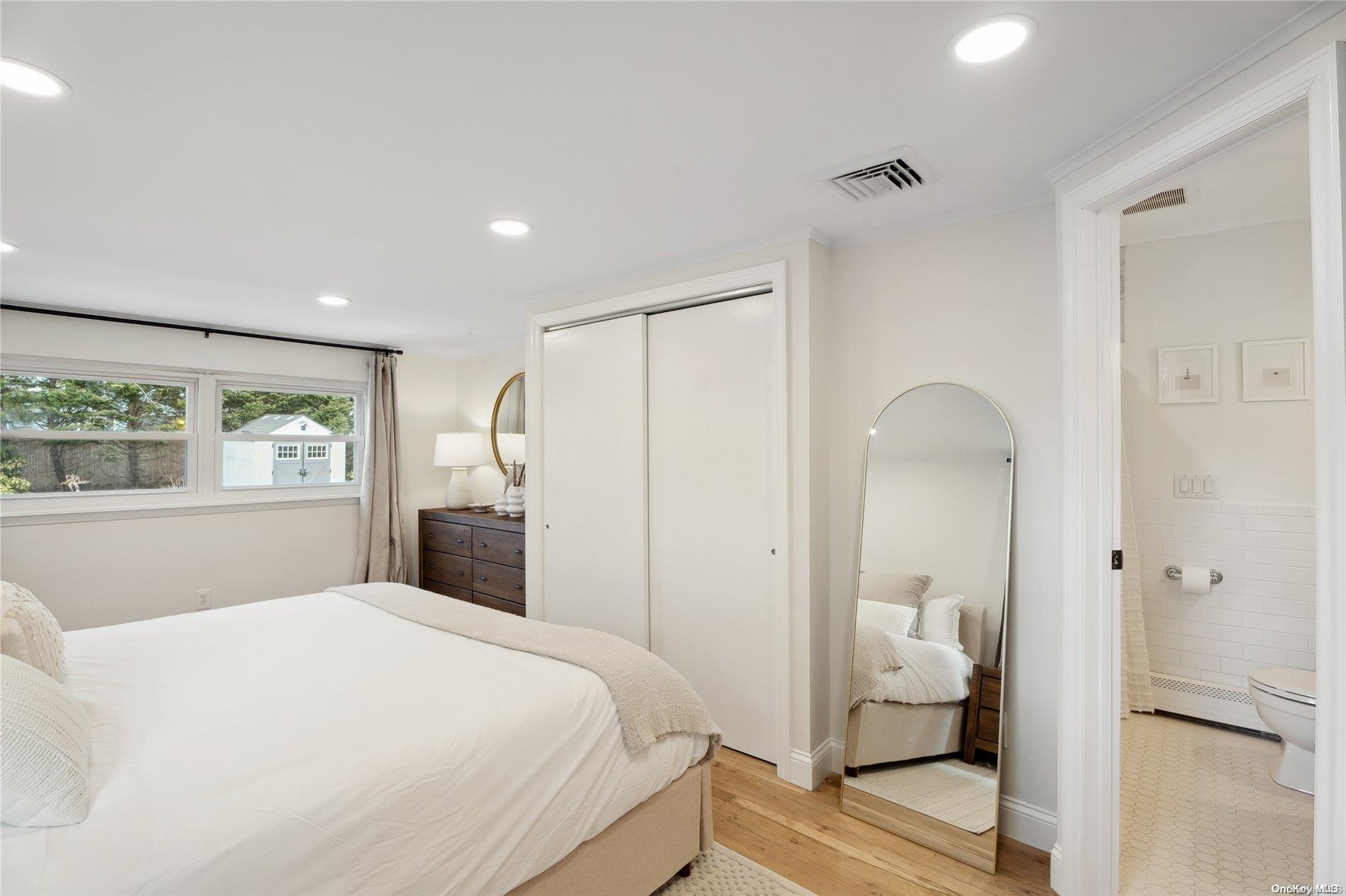 28 Argonne Road West Hampton Bays, NY 11946 - Photo 12 of 24 a bedroom with a large bed and wooden floor