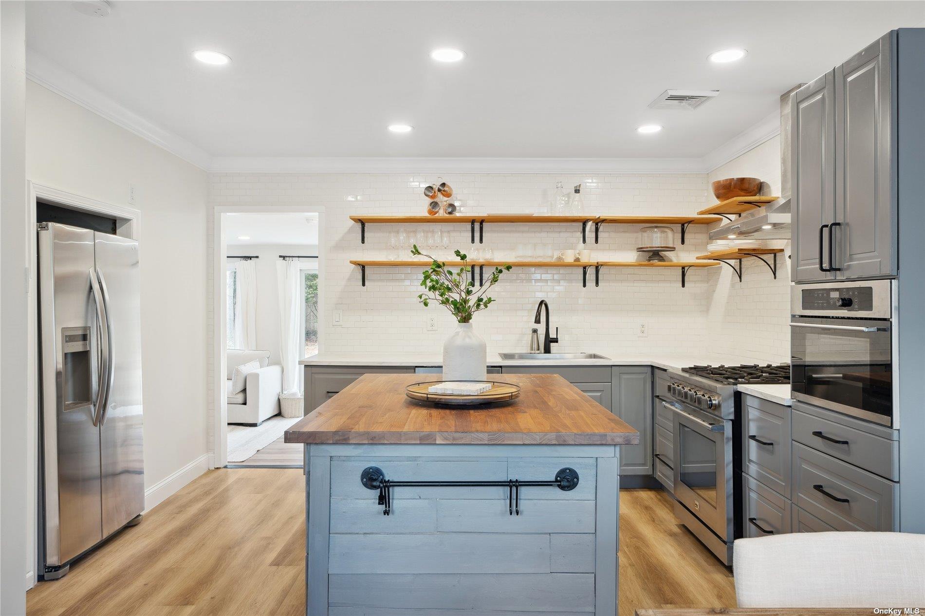 28 Argonne Road West Hampton Bays, NY 11946 - Photo 3 of 24 a kitchen with kitchen island stainless steel appliances a sink stove and refrigerator