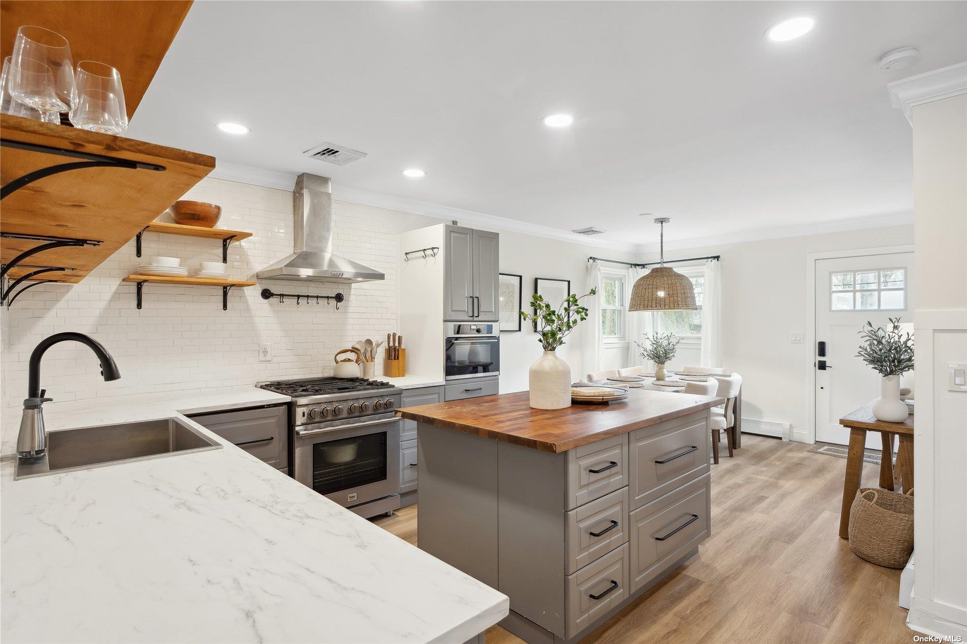 28 Argonne Road West Hampton Bays, NY 11946 - Photo 4 of 24 a kitchen with a sink stove and wooden cabinets